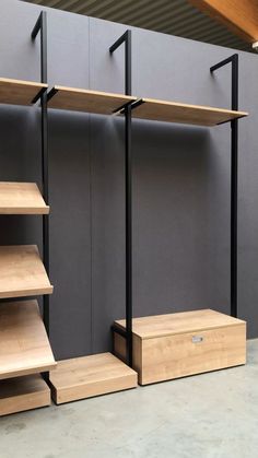 three shelving units with wooden shelves and metal brackets on the sides, in front of a gray wall