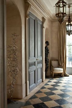 an elegant entry way with a checkered floor and chandelier