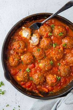 a skillet filled with meatballs covered in sauce and garnished with parsley