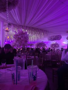 people are sitting at tables with purple lighting