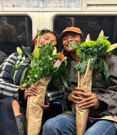 two people sitting on a train with flowers in their hands