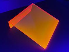 an orange and yellow plastic object sitting on top of a black table with blue lighting