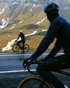 a person riding a bike on the road with mountains in the background