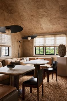 a living room filled with lots of furniture next to two large windows covered in shades of brown