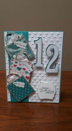 a birthday card with the number twelve and two tags on it, sitting on top of a wooden table