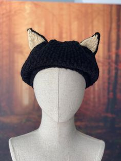 a white mannequin head wearing a black knitted hat with horns on it