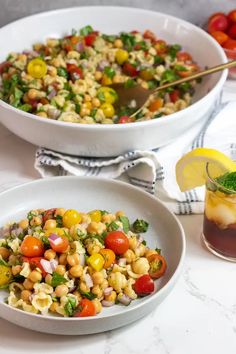 two white bowls filled with pasta salad next to a drink