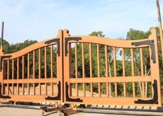 a large wooden gate sitting in the middle of a parking lot next to some trees