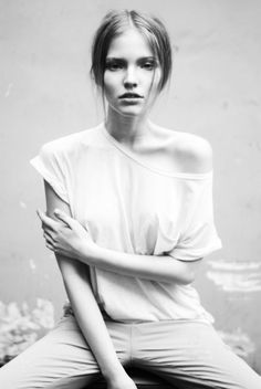 a black and white photo of a woman with her arms crossed sitting on a stool