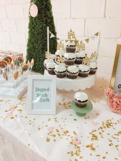 a table topped with lots of cupcakes next to a cake and candy bar