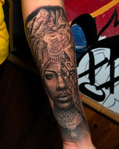 a woman's arm with a tattoo on it and an intricate headdress