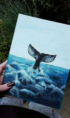 a person holding up a painting of a whale's fluff in the ocean