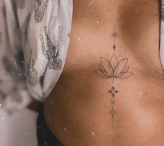 a woman's lower back with a flower tattoo on her left side ribcage