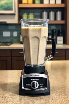 a blender sitting on top of a kitchen counter filled with brown liquid and ingredients