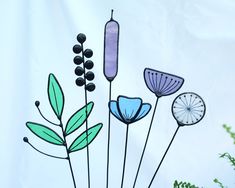 a group of glass flowers sitting on top of a green planter next to a white wall