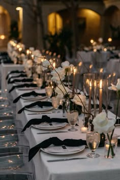 a long table is set with white flowers and candles