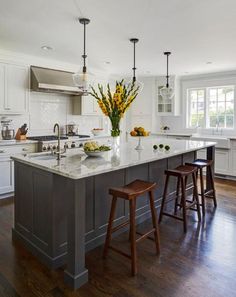 a large kitchen island with stools next to it and yellow flowers in the center