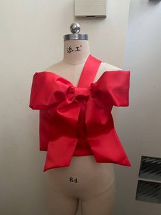 "Elevate your style with this vibrant red one-shoulder crop top, adorned with a dainty detachable big bow for a touch of charm. Perfect for a myriad of occasions, this unique piece effortlessly stands out, ensuring you shine brightly without being overlooked. Crafted from high-quality satin duchess, its design accentuates your feminine allure while providing a luxurious feel. Ideal for strolling confidently at glamorous events, celebrating milestones, or even embracing a romantic dinner. The lively red hue complements various festivities, be it Christmas, New Year, Chinese New Year, or Valentine's Day - offering you a versatile wardrobe choice. **Features and Benefits - Detachable big bow for diverse styling options. - Premium satin duchess material ensures a wrinkle-resistant and elegant Elegant Party Top With Bow, Elegant Party Tops With Bow Tie Back, Feminine Party Tops With Bow Detail, Spring Party Tops With Ribbon, Feminine Evening Tops With Bow Detail, Feminine Evening Tops With Bow, Fitted Party Tops With Ribbon, Chic Party Top With Detachable Bow, Chic Party Tops With Detachable Bow