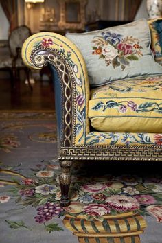 an ornately decorated couch sits in the middle of a room with floral rugs