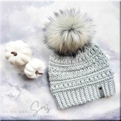 a knitted hat with two white pumpkins next to it on a gray background