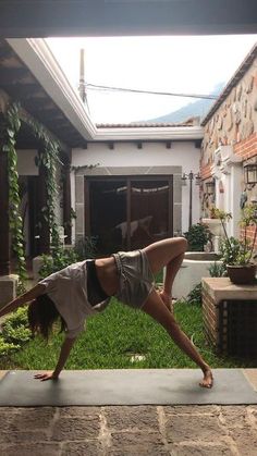 a woman is doing yoga outside in front of a house with her hands on the ground