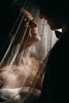 a man and woman standing next to each other under a veil