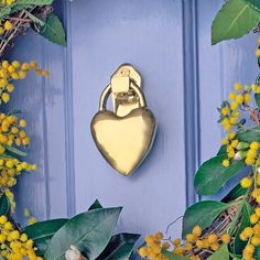 a blue door with a gold heart on it and yellow flowers in front of it