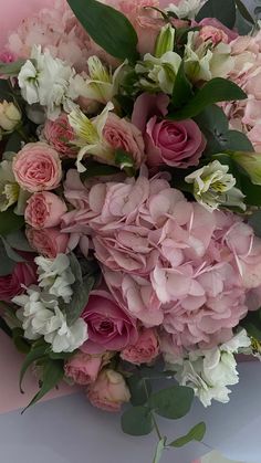 a bouquet of pink and white flowers sitting on top of a table