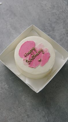 a white cake with pink frosting and two hearts in the middle on a plate