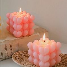 two pink candles sitting on top of a table next to a basket filled with balloons