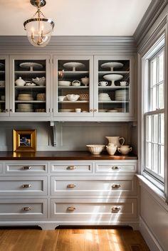 an empty kitchen with white cabinets and wood flooring, along with a chandelier hanging from the ceiling