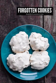 four pieces of meringue on a blue plate next to a wooden table top