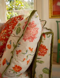 a close up of pillows on a couch in front of a window with green trim