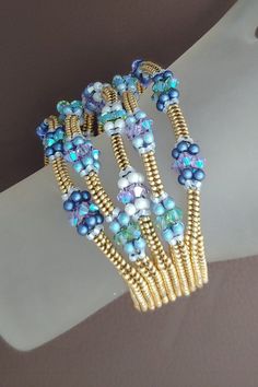 three bracelets with blue and green beads on them sitting on top of a white glove