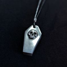 Small solid silver coffin pendant with skull on front. High polish finish. H: 30mm X W: 15mm X D: 3mm. No chain.