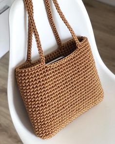 a brown crocheted bag sitting on top of a white chair