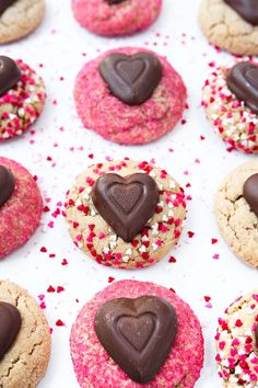 heart shaped cookies with sprinkles and chocolate in the middle on a white surface