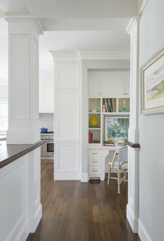 an empty kitchen with white cabinets and wood flooring on the walls, along with hardwood floors