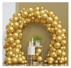 an arch made out of gold balloons with a potted plant in the center on a table