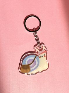 a keychain with an image of a snail on it's side and a pink background