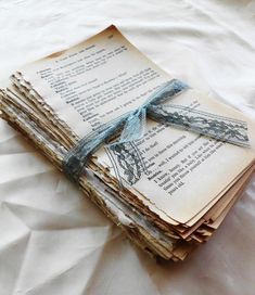 stack of old books tied with blue ribbon on top of white sheeted bedding