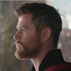 a close up of a person with a beard and wearing a uniform looking off into the distance