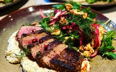 a plate topped with meat and vegetables on top of a table