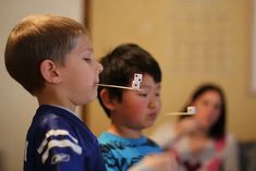 two young boys are playing video games with sticks in their mouths and one boy is looking at the camera