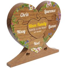 a wooden heart shaped puzzle with the names of family on it and flowers in the center