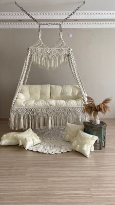 a white bed sitting on top of a wooden floor next to a potted plant