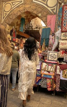 two women are walking through an outdoor market