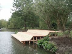 a wooden dock sitting in the middle of a body of water next to some trees