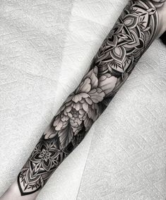 a black and white tattoo with flowers on the arm is shown in this image, it looks