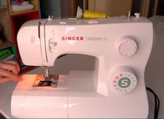 a woman is using a sewing machine to sew on the table in front of her